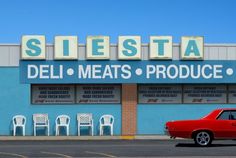 a red car parked in front of a deli