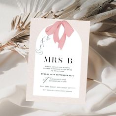 a wedding card with a pink bow on it and feathers in the background, as well as text that reads save the date