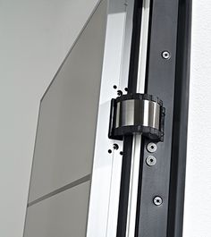 a close up of a metal door handle on a white and black building with windows