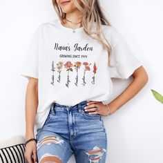 a woman wearing a white t - shirt that says namas garden with flowers on it