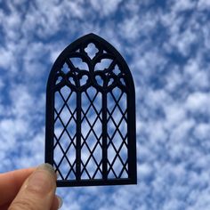 a hand holding up a small window in front of a blue sky with white clouds