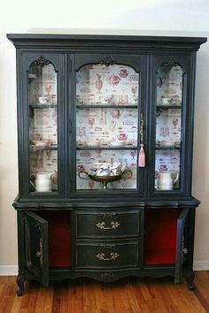 an old china cabinet is painted black and has red trimmings on the glass doors