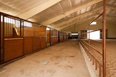 an empty horse barn with wooden stalls