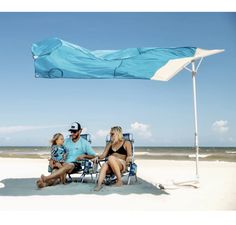 a family sitting under an umbrella on the beach