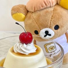 a teddy bear sitting next to a dessert in a glass bowl