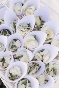 white flowers are arranged in paper bowls on a table