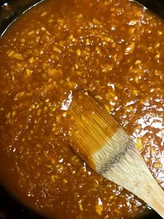 a wooden spatula in a pot filled with chili