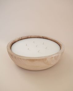 a wooden bowl filled with white candles