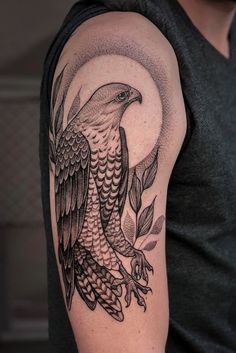 a man with a black and white tattoo on his arm holding an eagle in front of the moon