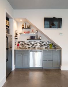 a kitchen with stainless steel appliances and open shelving above the sink, under a slanted ceiling