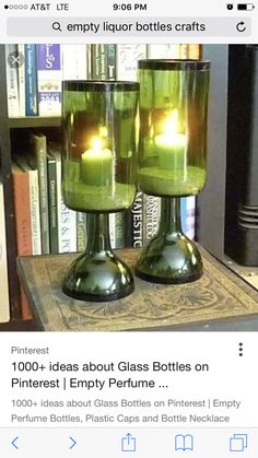 two green candles sitting on top of a table next to bookshelves and a book case