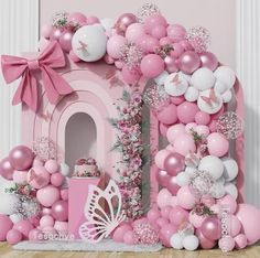 a pink and white balloon arch is decorated with balloons, streamers, and decorations