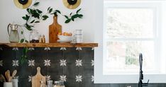 a kitchen with black and white tile, wooden cutting board, utensils and potted plants