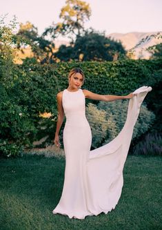 a woman in a white dress is standing on the grass