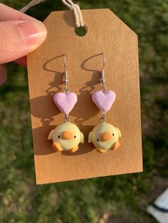 a pair of bird earrings with hearts hanging from it's earwires on a card