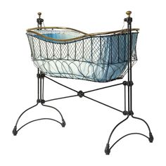 an iron and glass baby crib on wheels with blue fabric in the bottom section