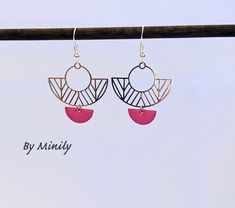 two pairs of earrings hanging from a hook on a wooden stick with the words by mindiy written below it