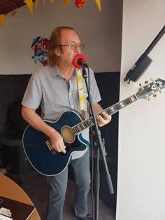 a man standing in front of a microphone while holding a guitar