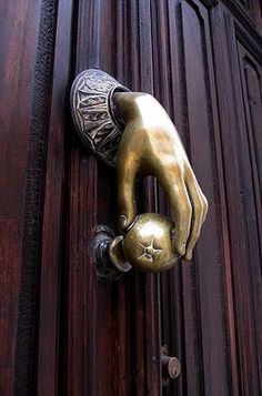 a close up of a door handle on a wooden door with a metal knocket