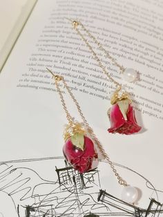 two necklaces with flowers and pearls hanging from them on top of an open book