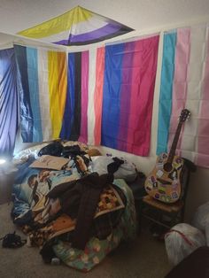 a room with several colorful flags hanging from the ceiling and clothes strewn on the floor