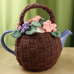 a knitted teapot cover with flowers on it