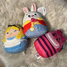 three stuffed animals sitting on top of a white rug