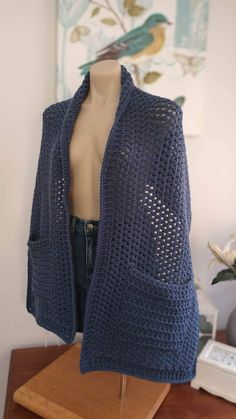 a mannequin wearing a blue crocheted jacket on top of a wooden table