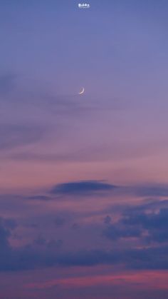 an airplane is flying in the sky at dusk with a crescent moon visible above it