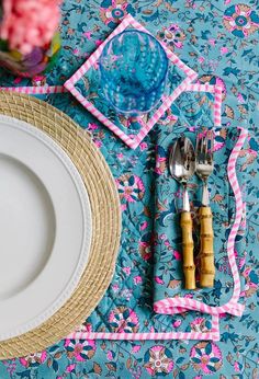 a place setting with utensils and napkins on a blue floral table cloth