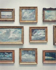 several paintings are hanging on the wall in front of each other, with clouds above them