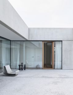 an empty room with glass walls and white furniture on the floor in front of it