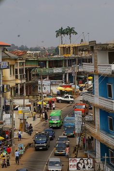 a city street filled with lots of traffic next to tall buildings and palm trees in the background