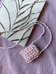 a book and necklace laying on top of a purple blanket next to a white notebook