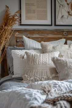 a bed with white pillows and blankets on top of it next to two framed pictures