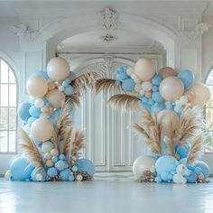 an arch made out of balloons, feathers and other items in blue and white colors