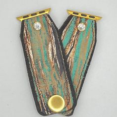 two pieces of leather with gold trim and diamond studs on each side, sitting next to each other