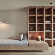 a bed sitting next to a wooden shelf filled with books