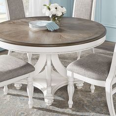 a dining room table with chairs and a vase on it's centerpiece in front of a window