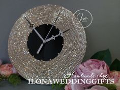 a black and white clock sitting on top of a table next to pink flower bouquets