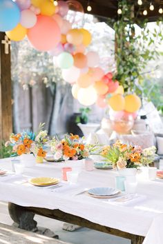 the table is set with colorful balloons and plates