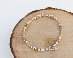 "This bracelet features a variety of sterling silver and gold vermeil beads strung in a flowing sequence of symmetry. Finished with a secure sterling silver lobster clasp and a cluster of coordinating charms. Perfect to wear by itself or layered with other bracelets for a stacked look. A classic piece that transitions seamlessly from day to night. Total length measures 7 5/8\". Sterling silver is .925 pure silver. Gold vermeil is 14k-24k gold plated sterling silver. See more mixed metal jewelry Gold Sterling Silver Beaded Bracelets With Round Beads, Gold Beaded Sterling Silver Bracelets, Gold Sterling Silver Beaded Bracelets, Gold Bracelet With Tiny Beads In Sterling Silver, Bracelet With Charms, Bali Silver, Mixed Metal Jewelry, Hill Tribe Silver, Silver Bead Bracelet