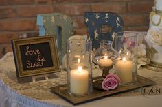 a table topped with candles and pictures next to a sign that says love is sweet