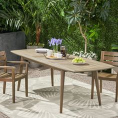 an outdoor dining table with chairs and plates of food on it in the middle of a garden