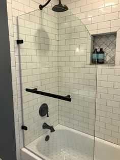 a white tiled bathroom with black fixtures and glass shower door, along with a bathtub