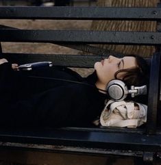 a woman with headphones laying on a bench