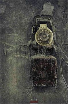 an old cell phone sitting on top of a dirty wall with water running down it