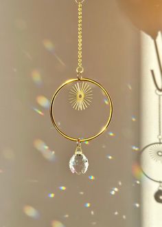 a gold plated metal wind chime hanging from a chain with a crystal drop