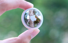 a person holding an apple logo in their left hand and looking at it through the lens