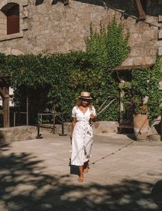 a woman in a white dress and hat walking